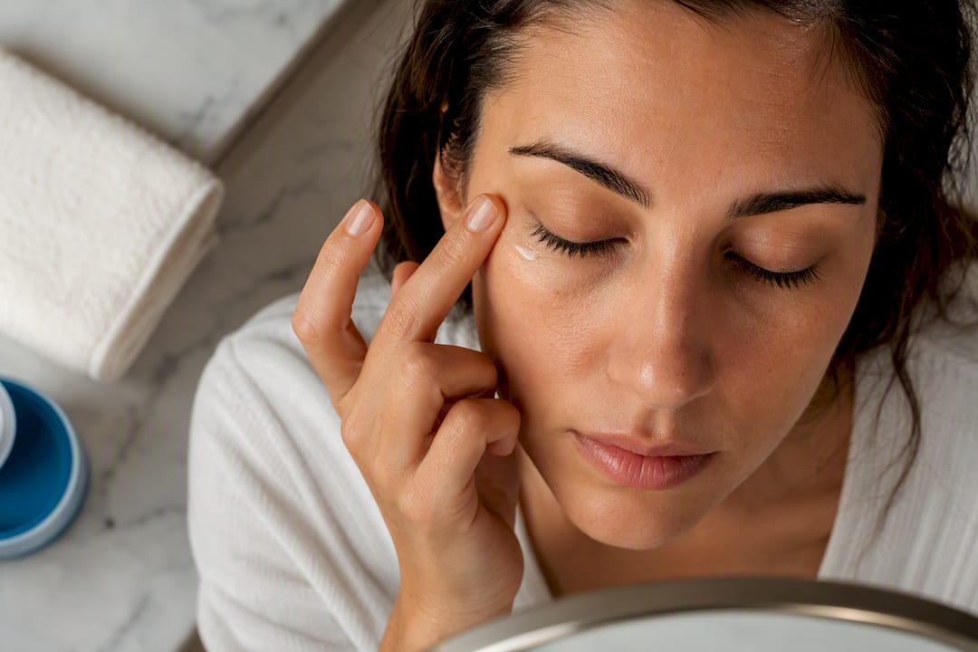 Finger applying retinol beneath the eye