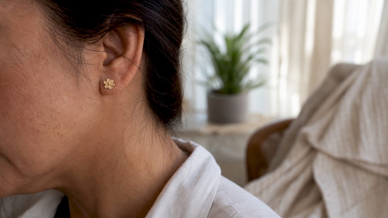 Side profile of woman wearing gold stud earring