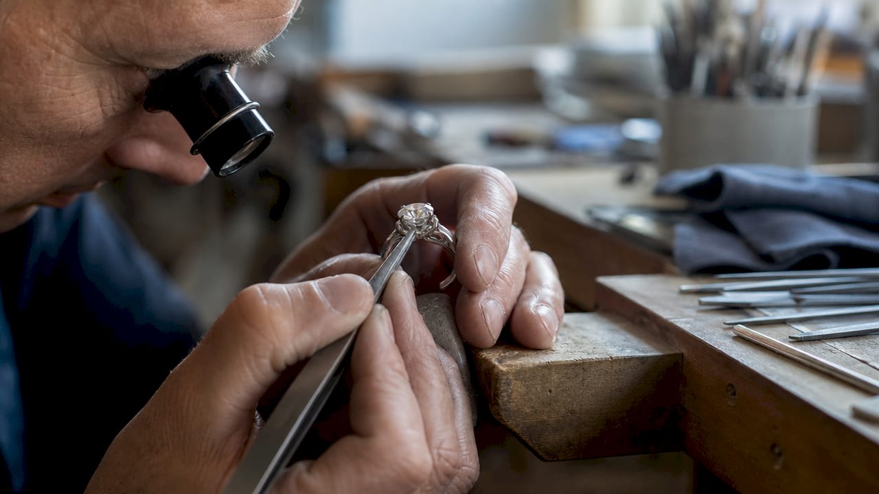 Jeweler hand-setting diamond in gold ring