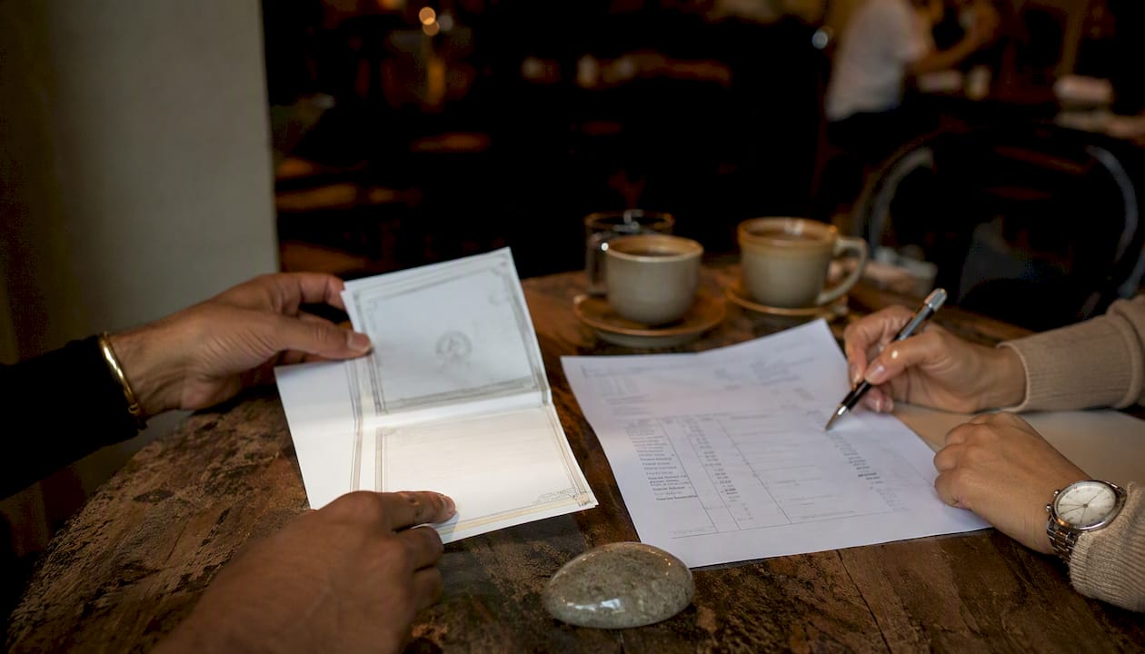 Hands reviewing gold certification documents overhead