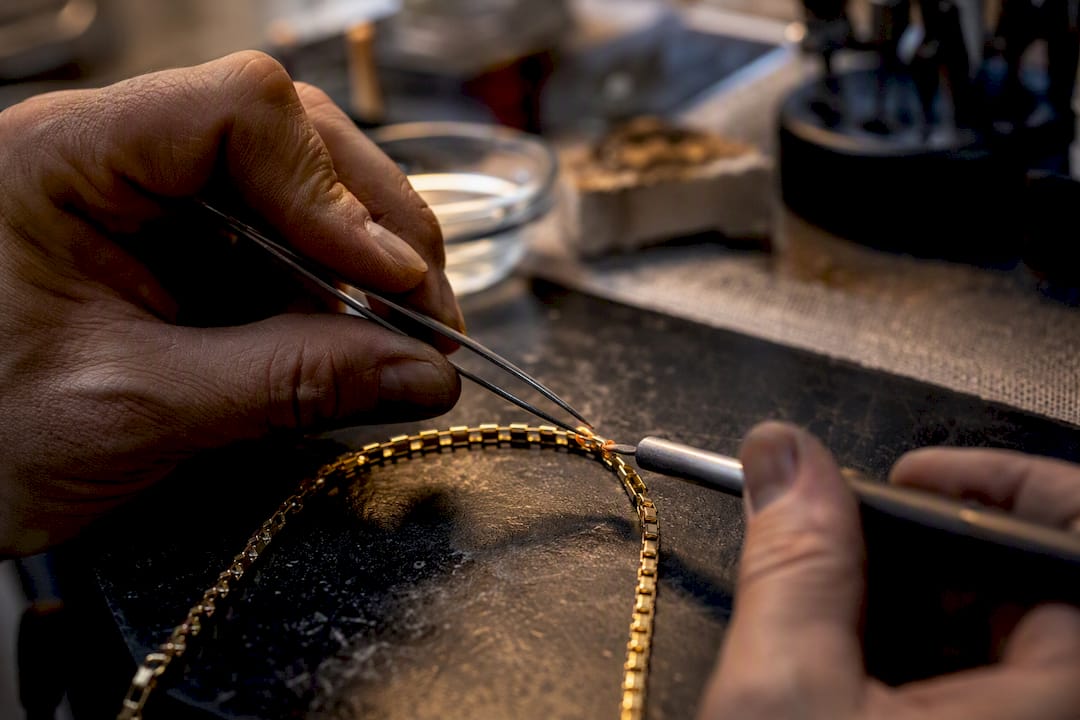 Jeweler repairing gold chain link close-up