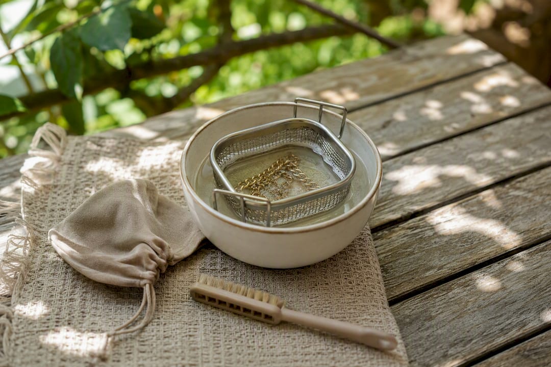 Gold chain in cleaning basket with jewelry care tools