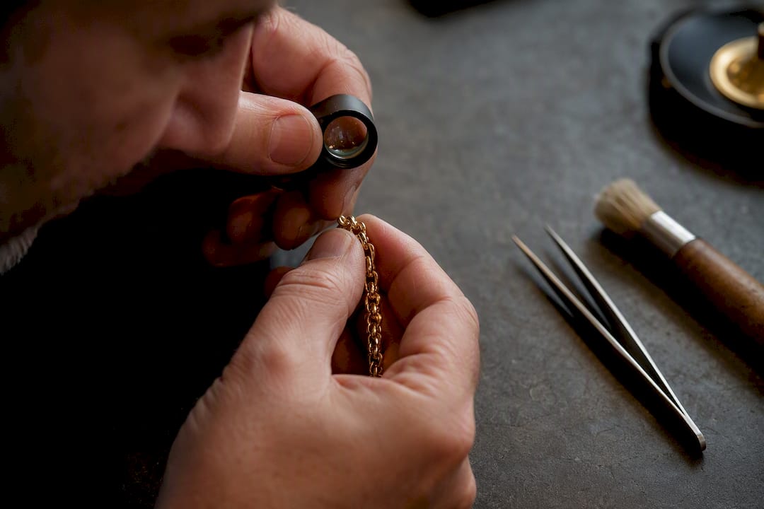 Jeweler inspecting prong on gold chain