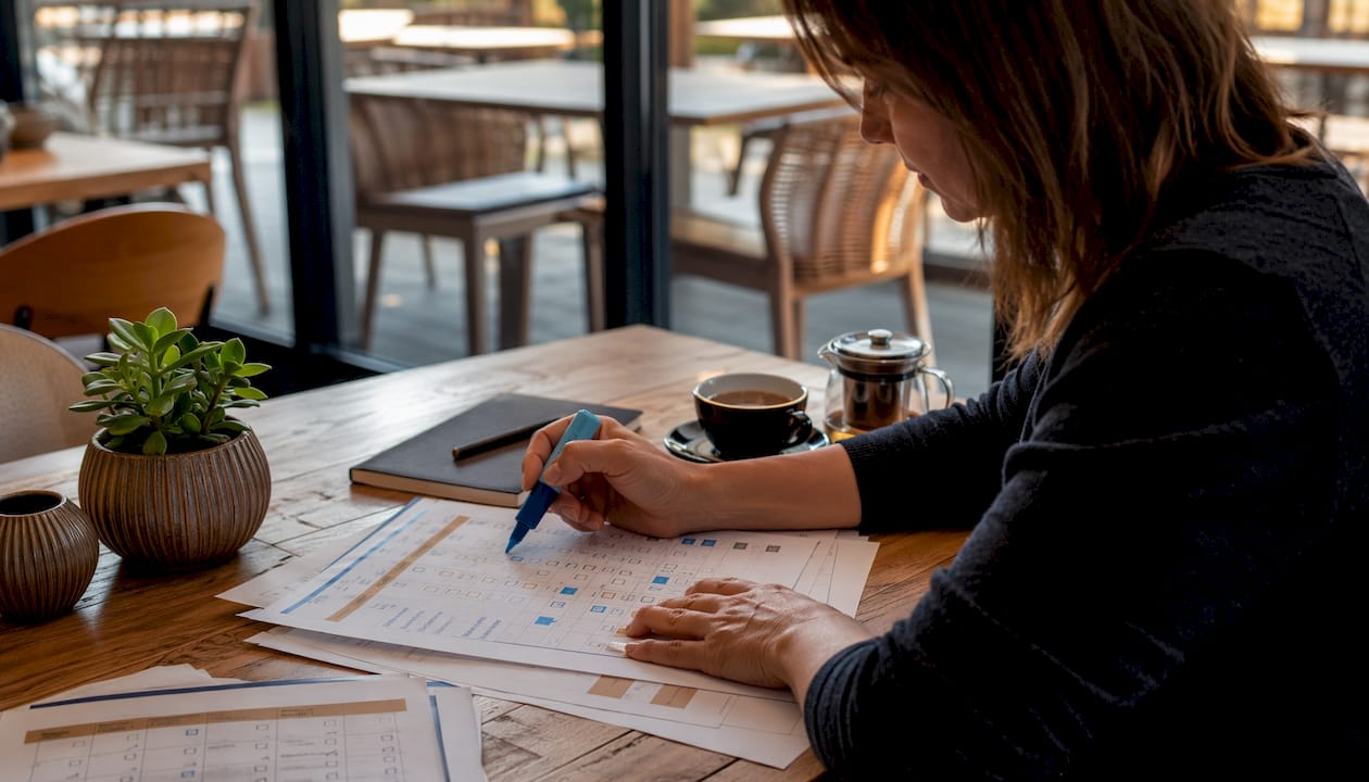 Hands marking fitness tool features on documents