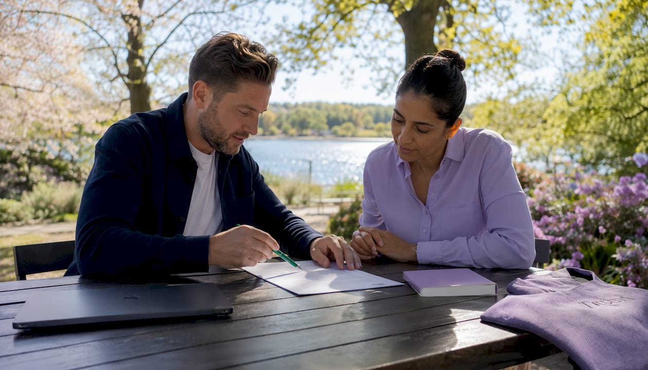 Under mötet pekar flera händer mot kontraktet på bordet.
