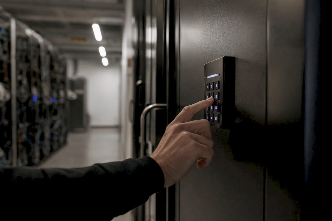 Hand som trycker på ett elektroniskt knappsats på dörren till serverrummet