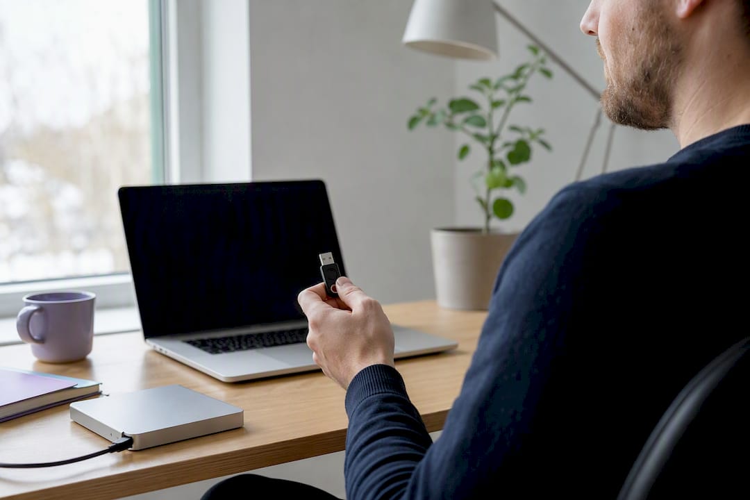 Hand som håller en USB-säkerhetstoken nära en bärbar dator