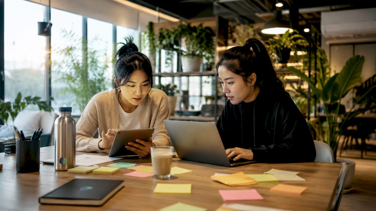 Two influencers collaborating over digital content in café