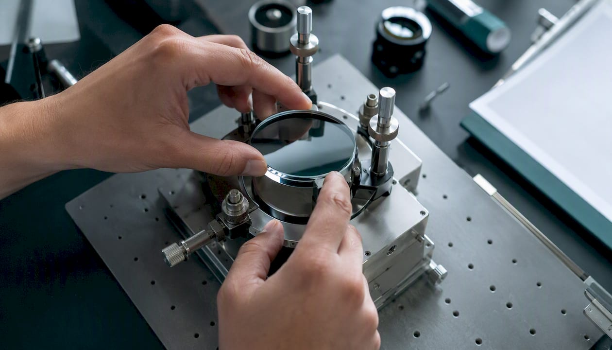 Hands positioning precision glass optic in compliant mount