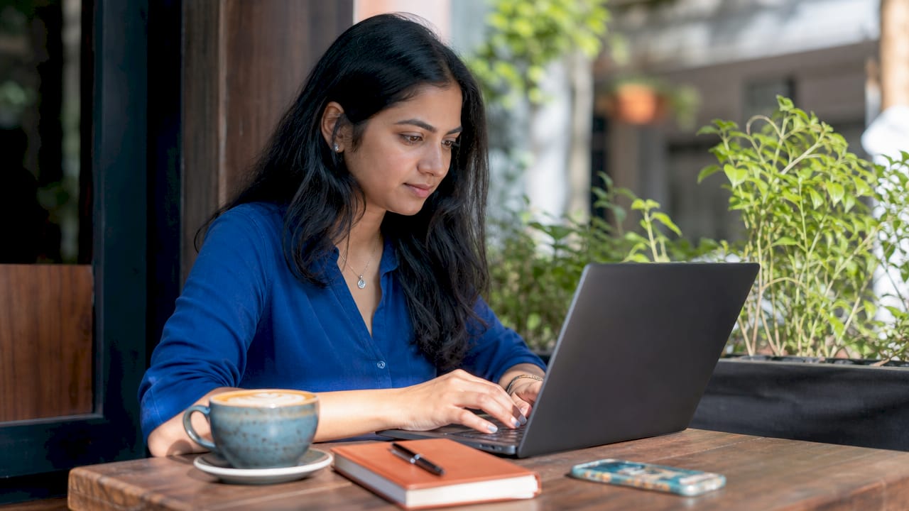Hands typing laptop in café setting