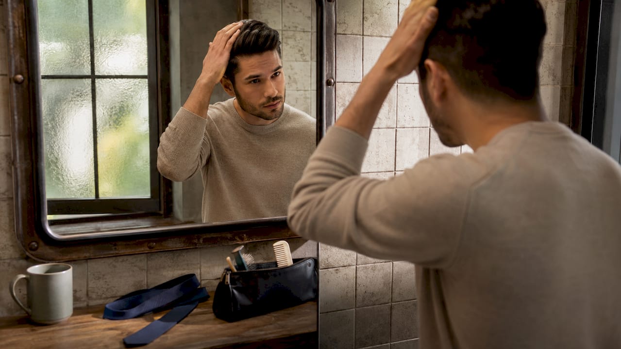 Man grooming in bathroom mirror before photoshoot