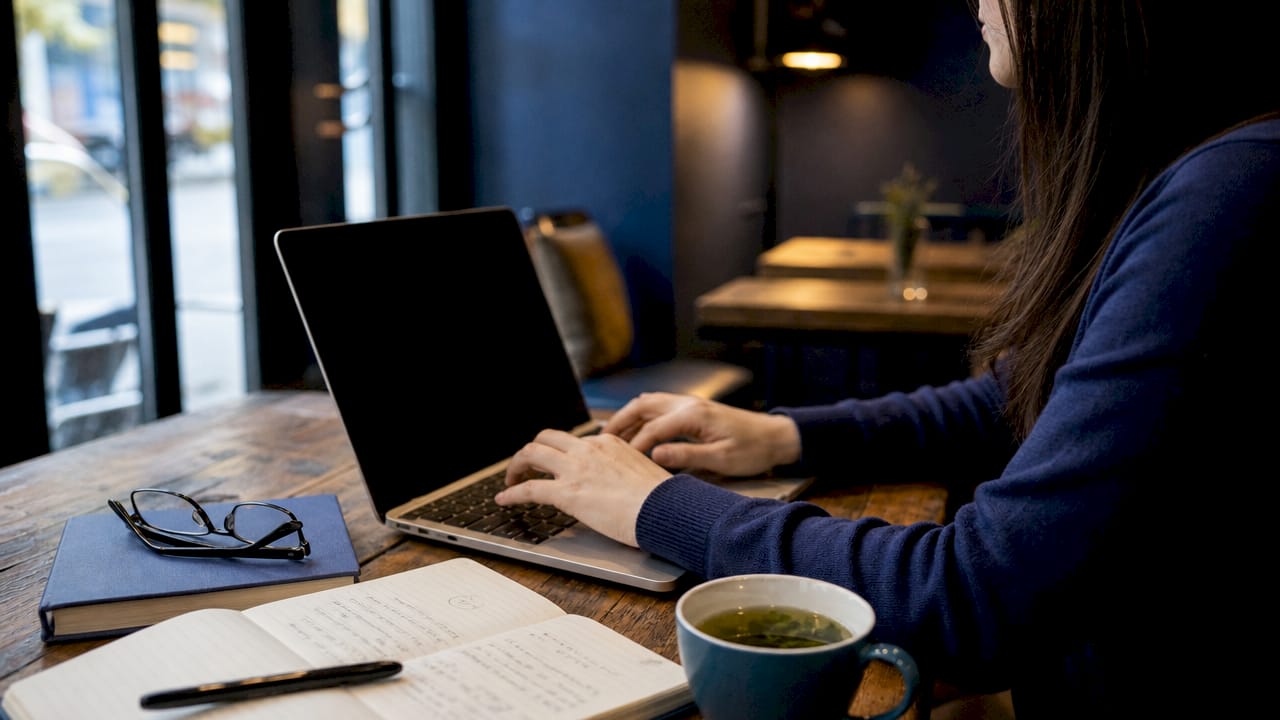 Hands typing author bio on laptop in home office