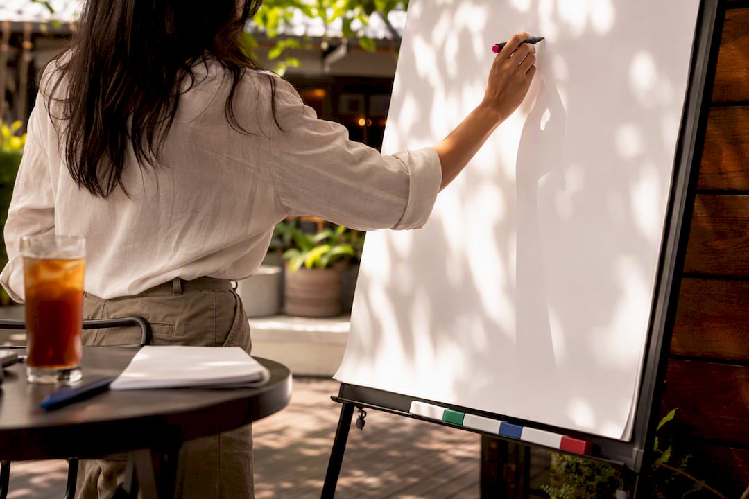 Hands writing question headings on flip chart