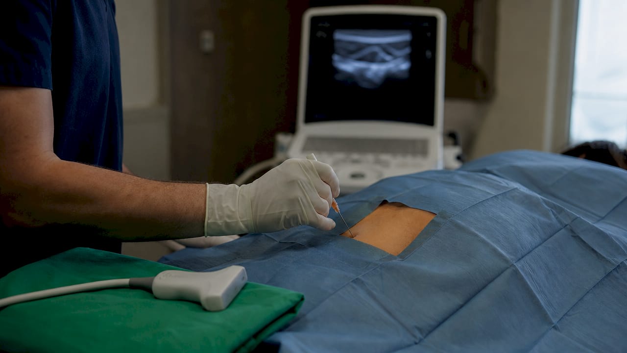 Gloved hand preparing injection with ultrasound guidance