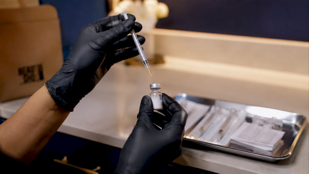 Close-up of hands mixing Botox vial with saline