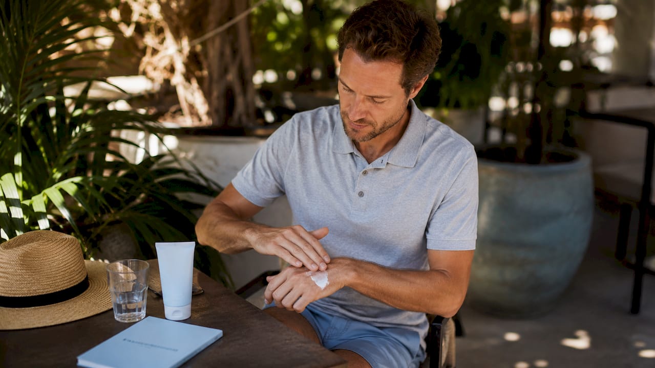 Man applying sunscreen on balcony