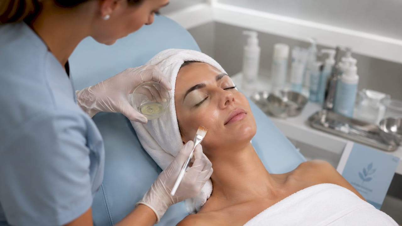 Hands applying medical skin peel treatment