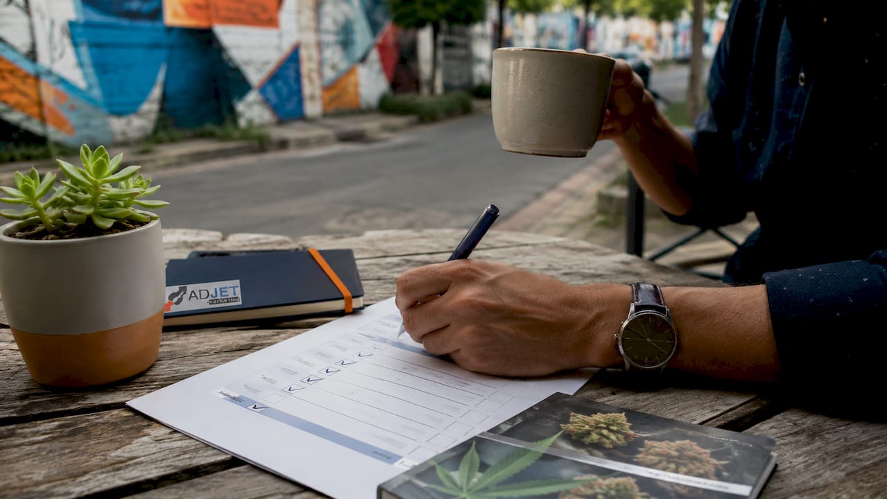Overhead view of hands working on local SEO checklist outdoors