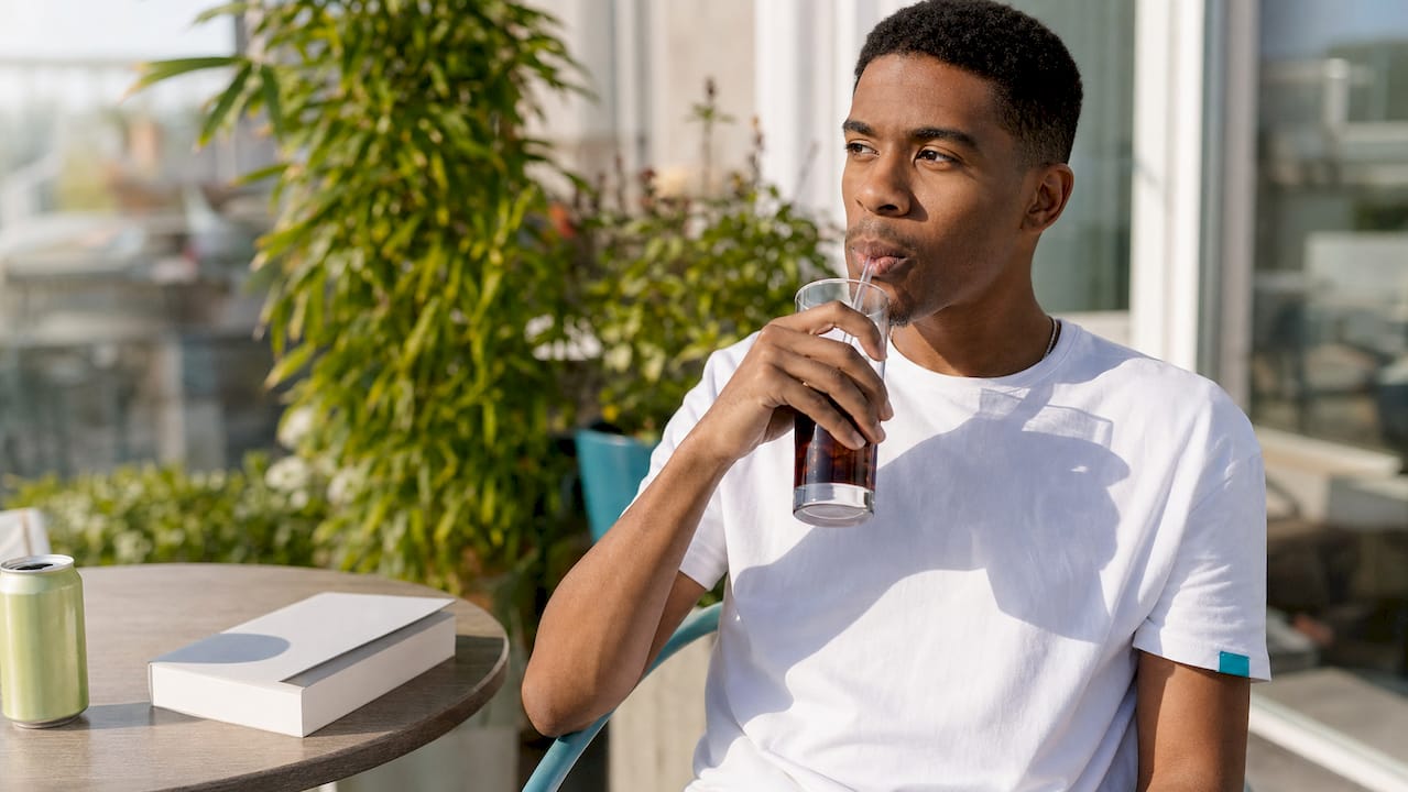 Man drinking dark beverage with straw after whitening