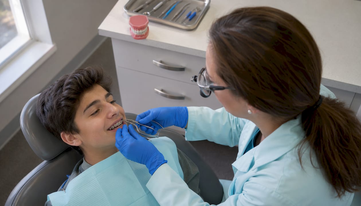 Orthodontist adjusting braces for teenage patient