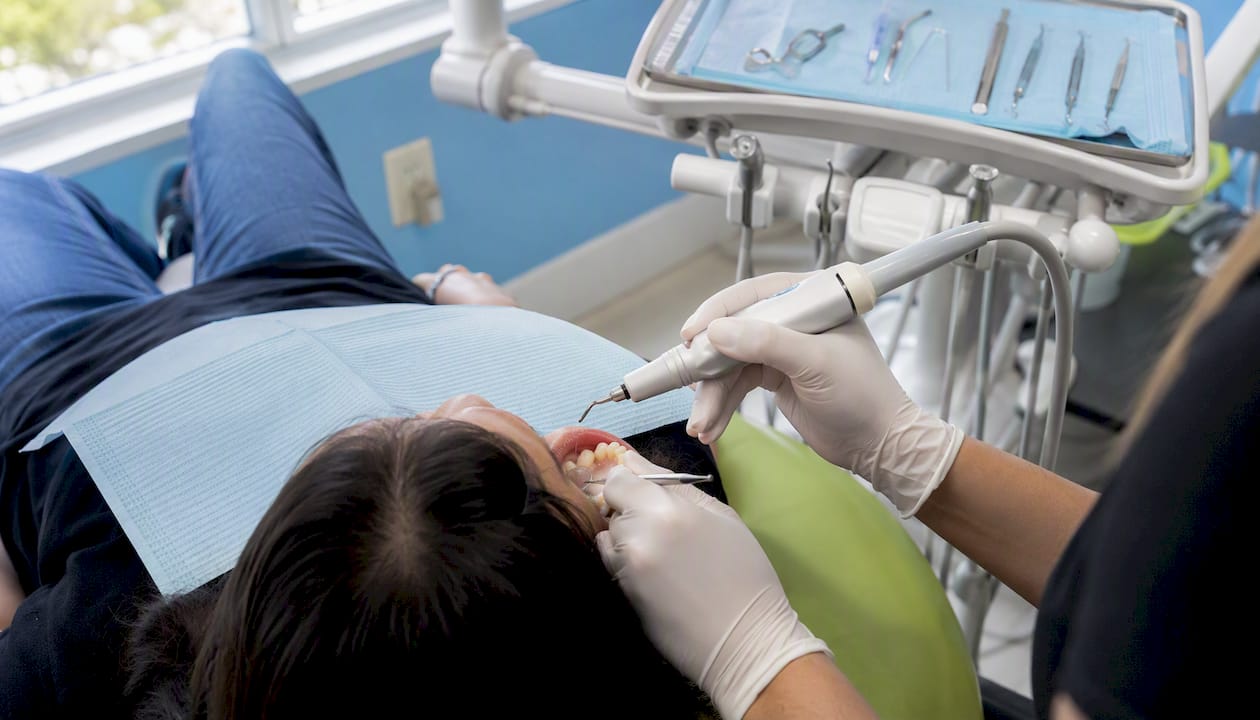 Dental hygienist using scaler to remove plaque
