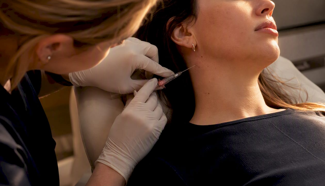 Nurse injecting filler into jawline using blunt cannula