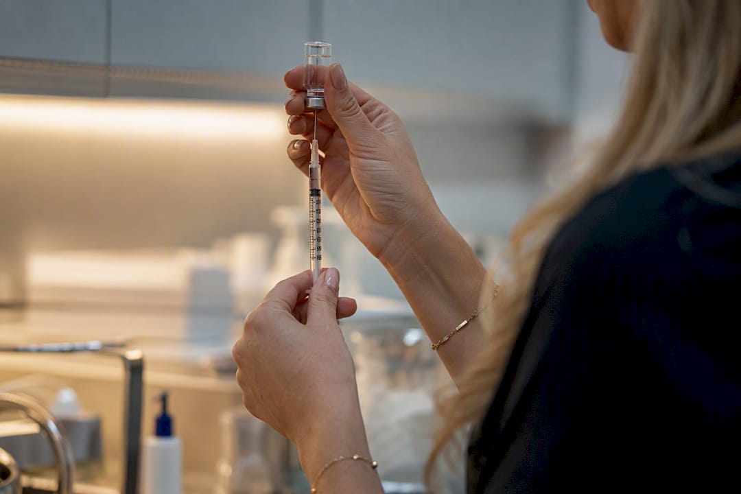 Hands measuring lip filler syringe volume