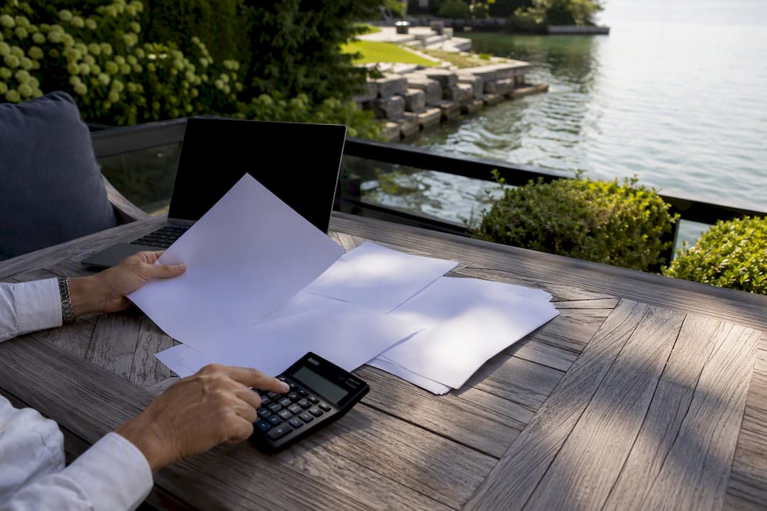 Hands adjusting mortgage documents near waterfront