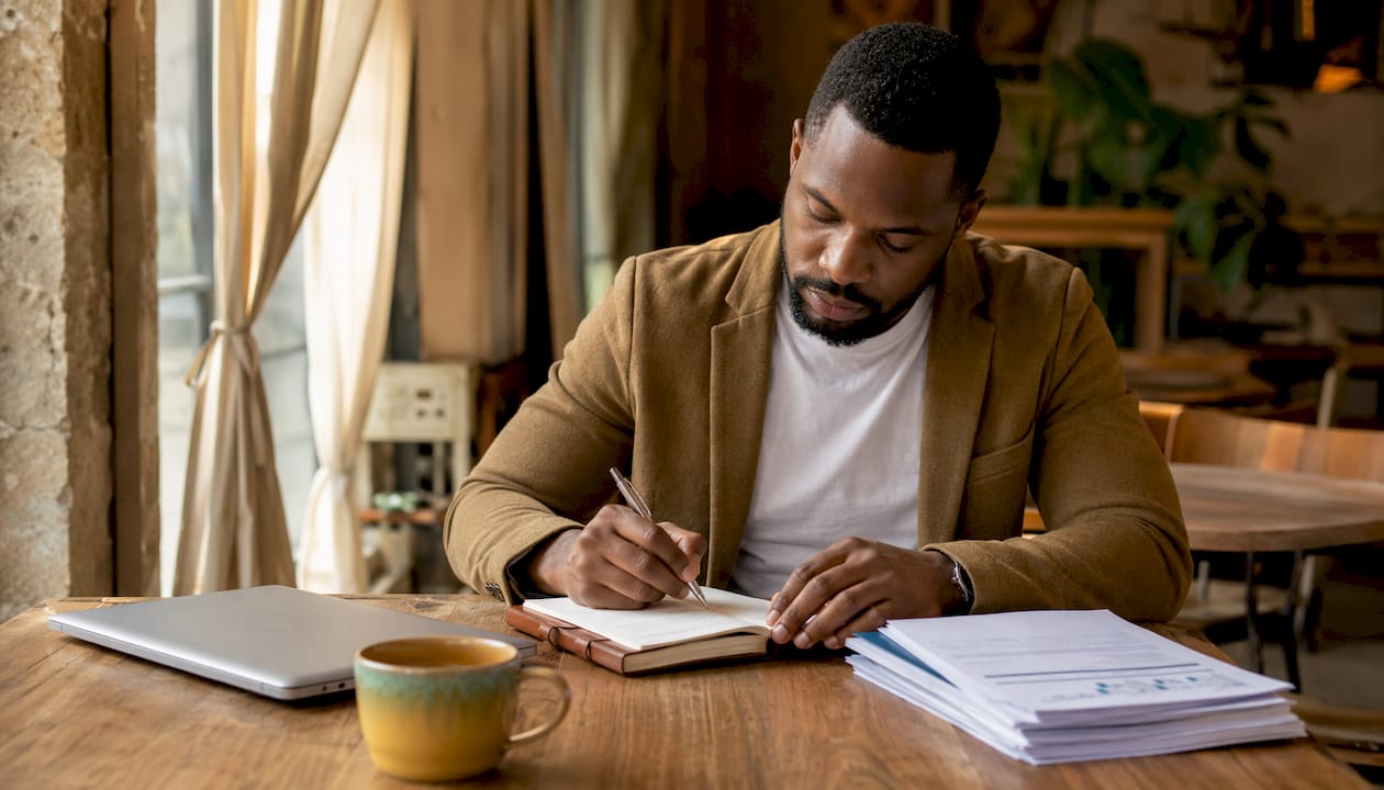 Man taking notes on 5 Cs of credit at home office