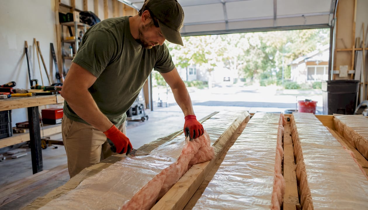 Types of Home Insulation: What to Use Where and Why 2026 Lizard's Lunch Hands cutting and fitting fiberglass insulation
