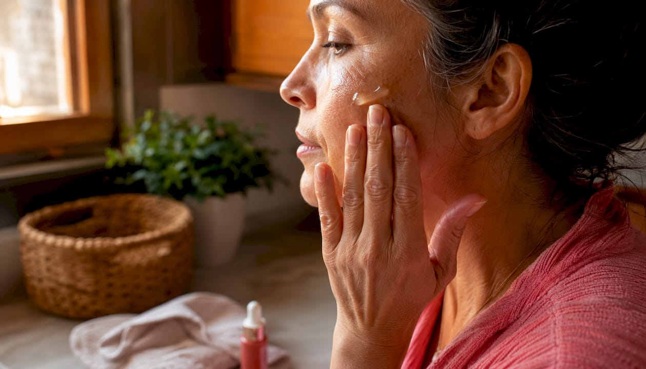 Πλάνο με γυναικεία χέρια που απλώνουν serum βιταμίνης C στο πρόσωπο