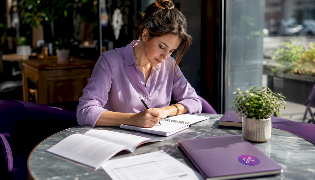 Person writing resume bullets with notes and laptop