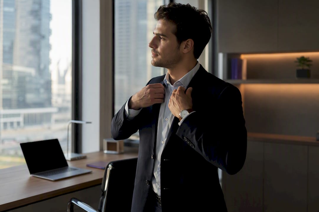 Person buttoning navy blazer