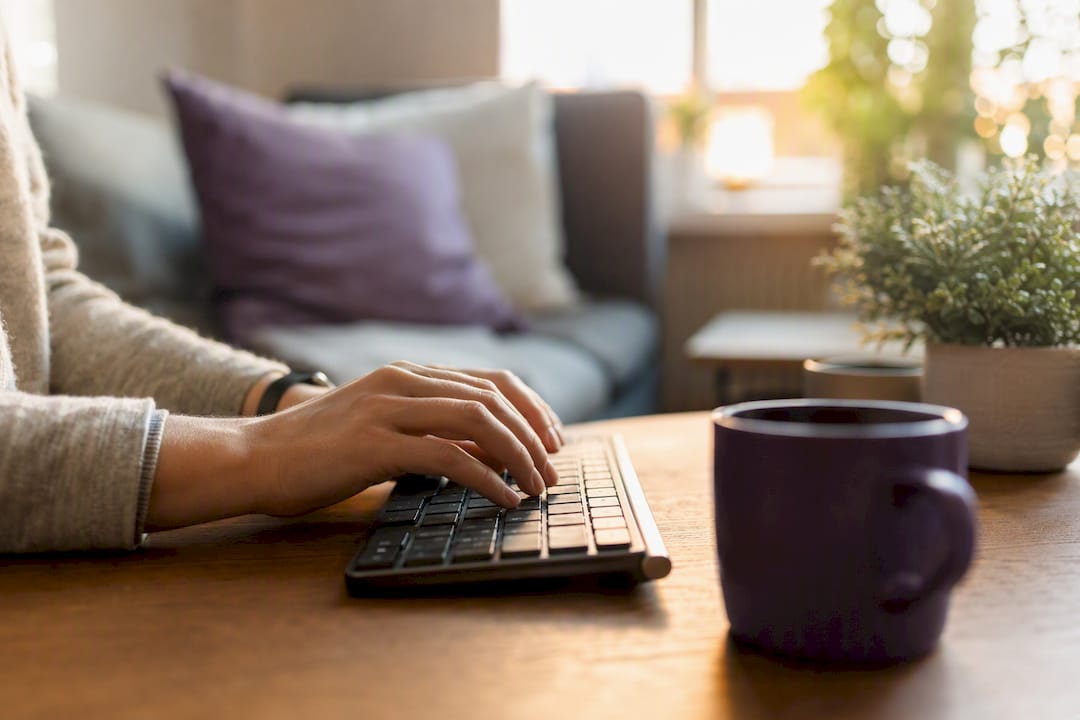 Hands typing carefully on keyboard with dim screen