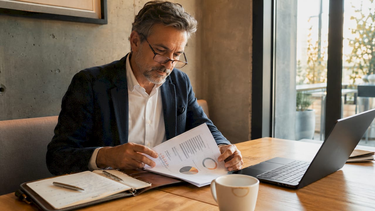 Un analyste métier en pleine étude d’un rapport papier présentant des visualisations de données.