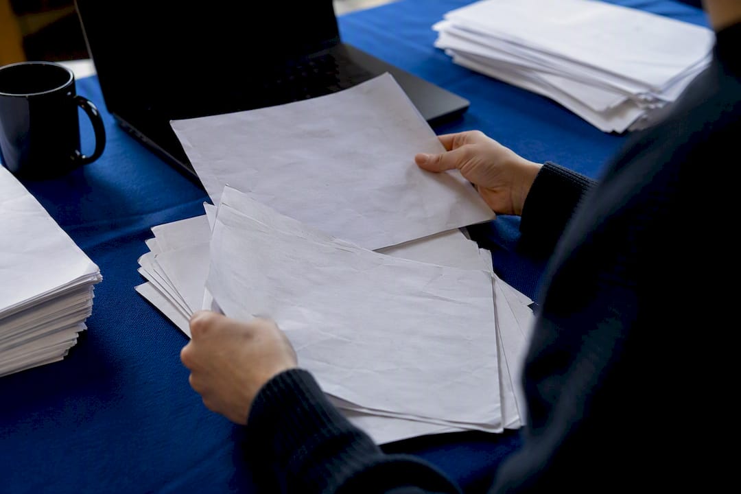 Hands sorting campaign fact sheets for quality control