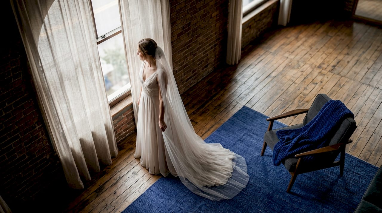Bride near window in sunlit loft studio