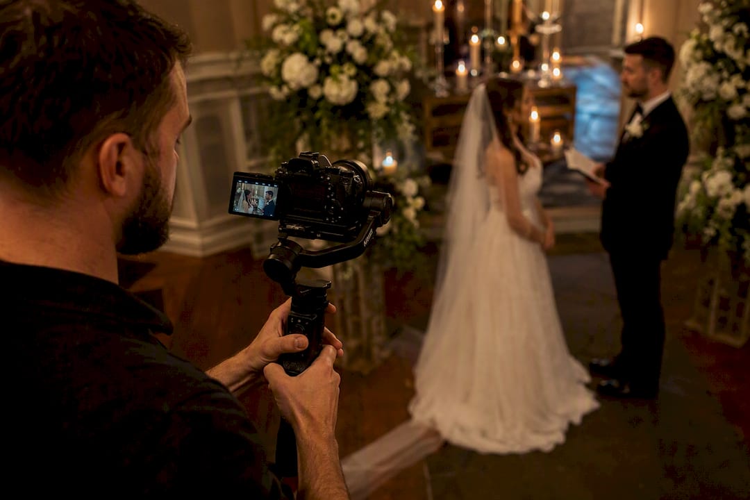 Videographer filming wedding vows outdoors