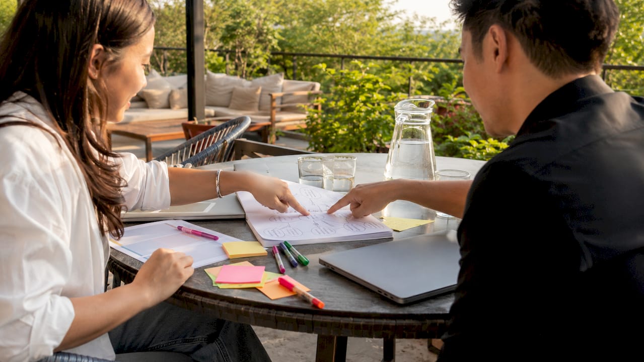 Hands pointing at marketing goal worksheets on table