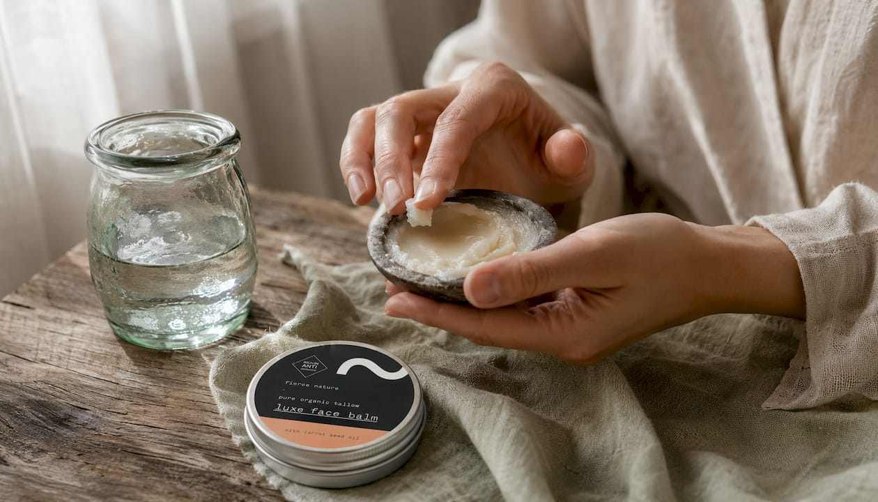 Hands scooping face balm from ceramic jar