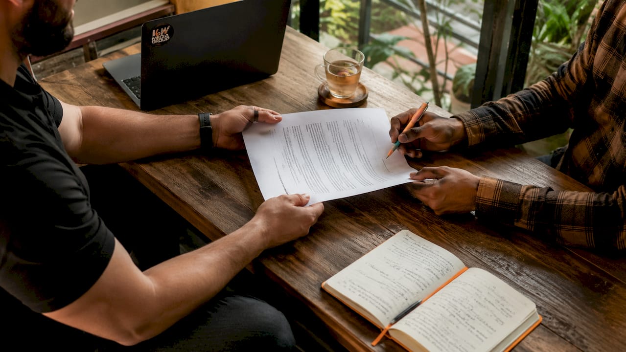 Hands exchanging signed media partnership agreement