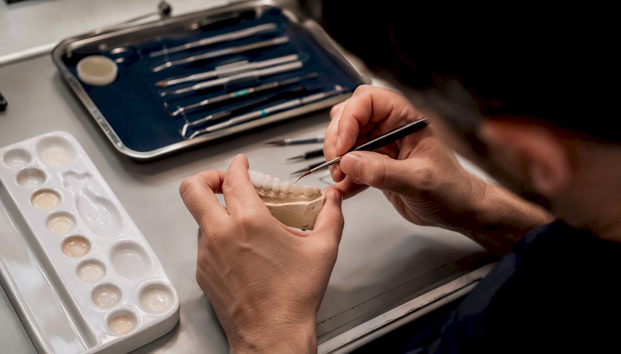 Il dentista applica la finitura ceramica su un modello dentale.