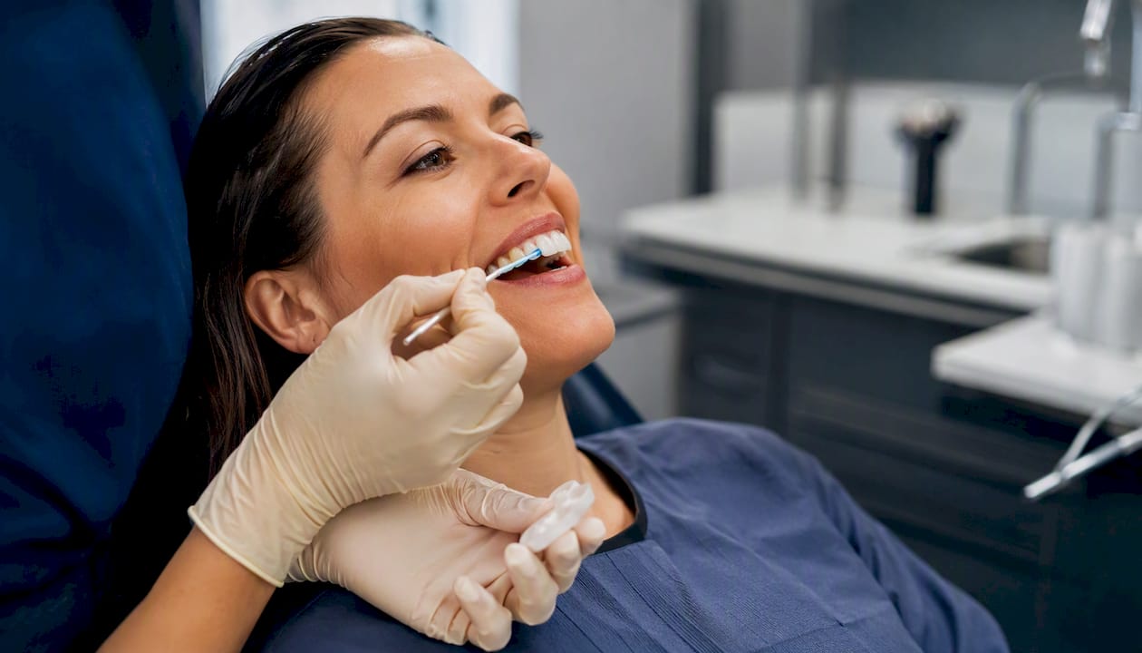 Mani che stendono un gel desensibilizzante sui denti