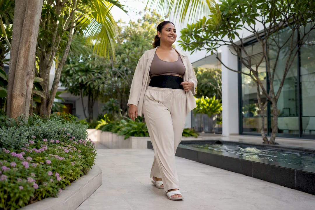 Patient walking gently in clinic hallway after abdominoplasty