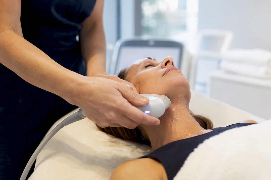 Professionista medico che applica un dispositivo a ultrasuoni sul viso del paziente