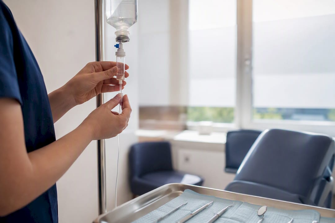 Hands adjusting IV sedation drip in clinical dental room