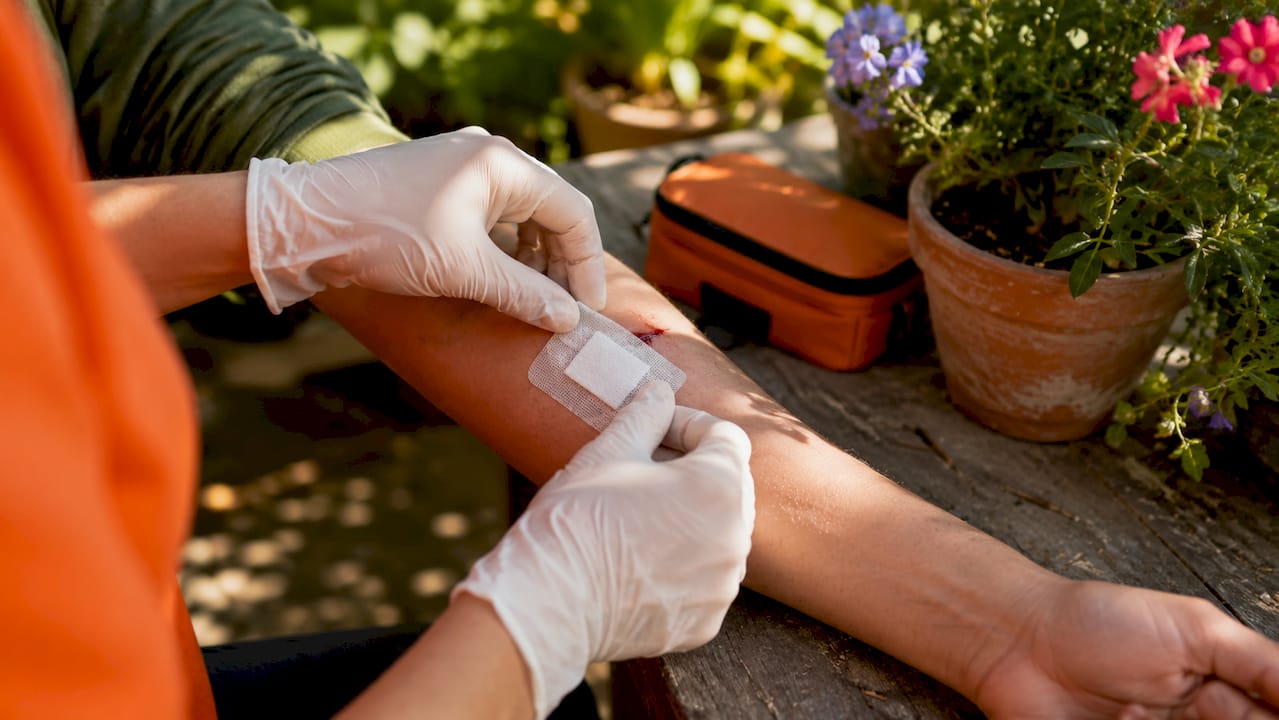 Hands applying sterile dressing to wound