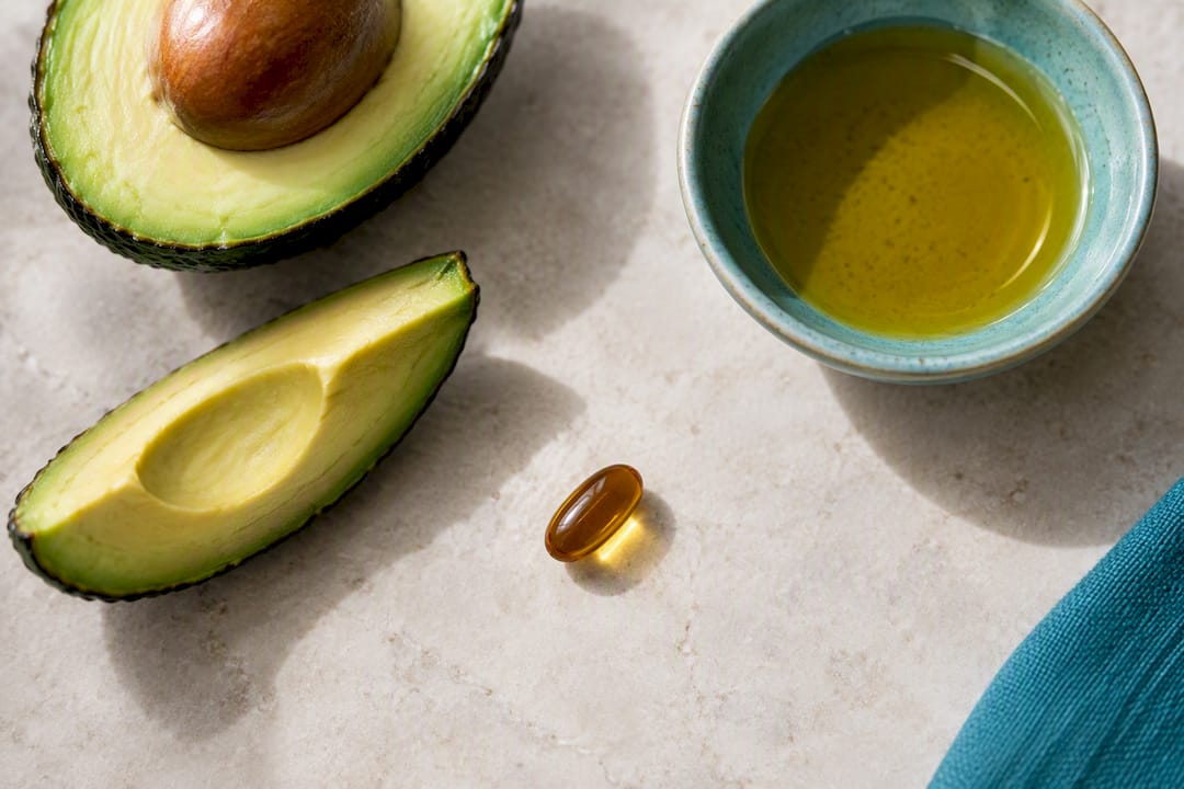 CoQ10 softgel beside avocado and olive oil