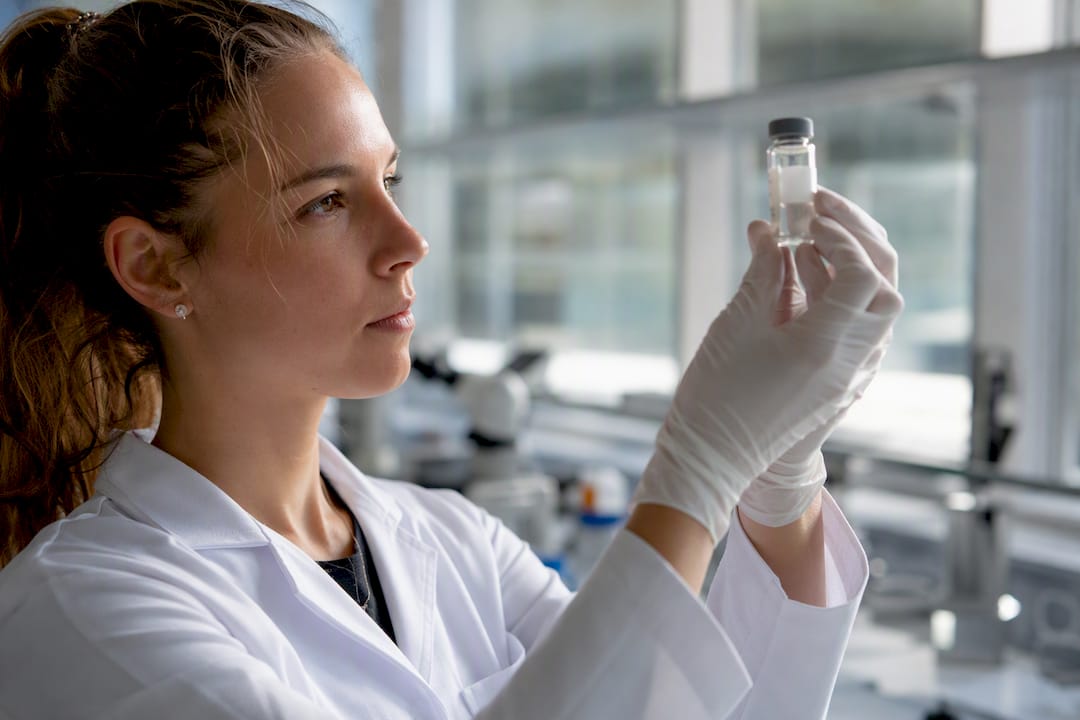 Technician inspecting peptide vial label in lab