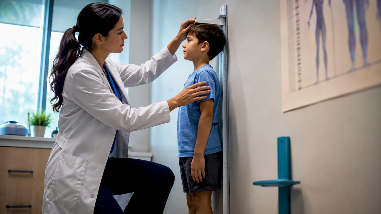 Clinician measuring child's height in endocrinology clinic
